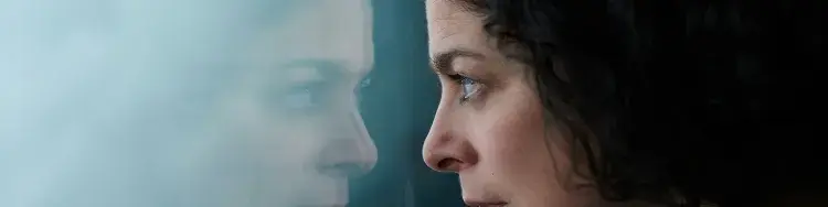 una mujer viendo su reflejo en la ventana